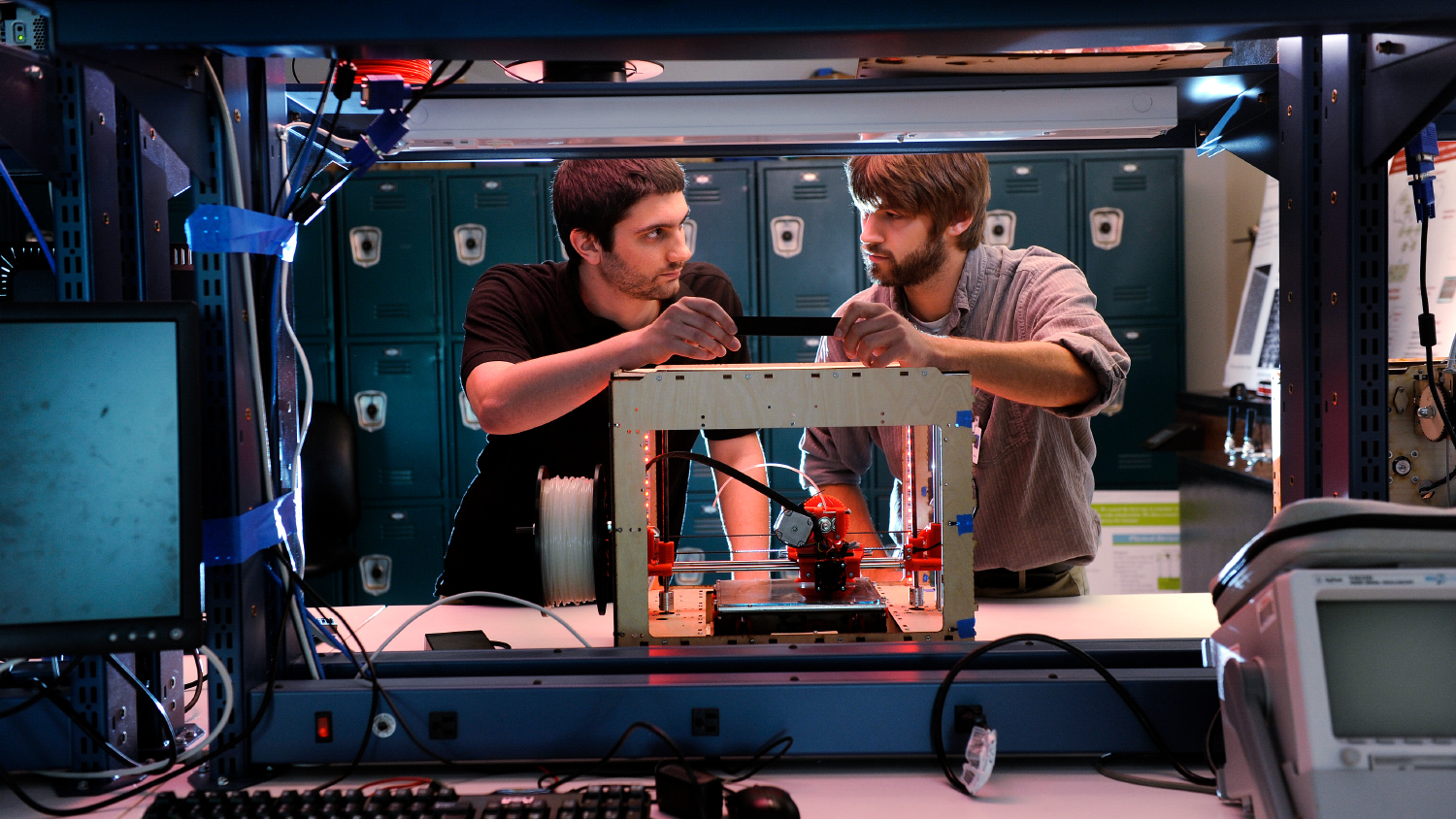 Two students work with a 3D printer on NC State's campus.