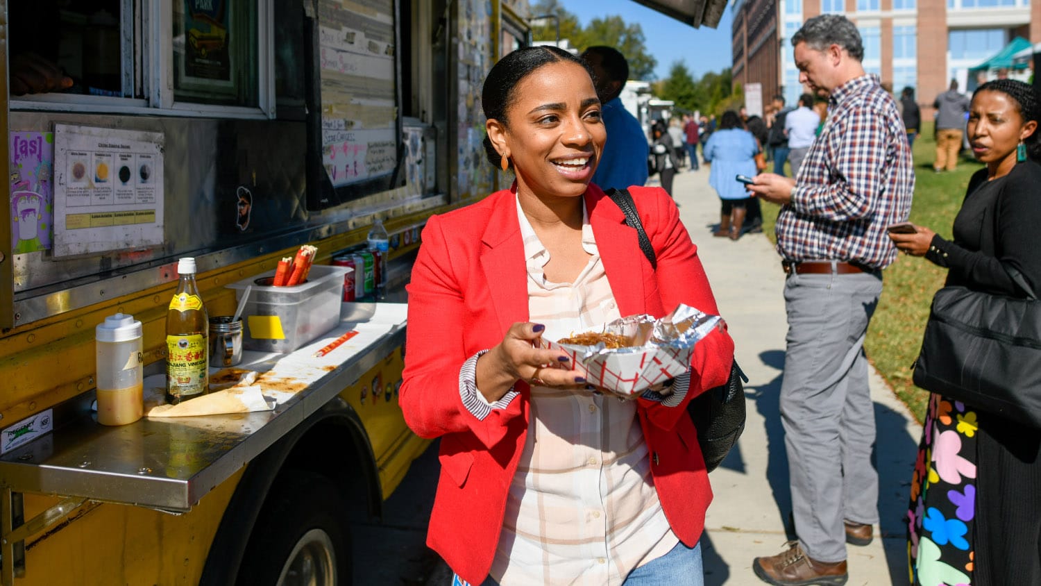 A woman enjoys a dish served from a food truck during a Food Truck Rodeo on Centennial Campus.
