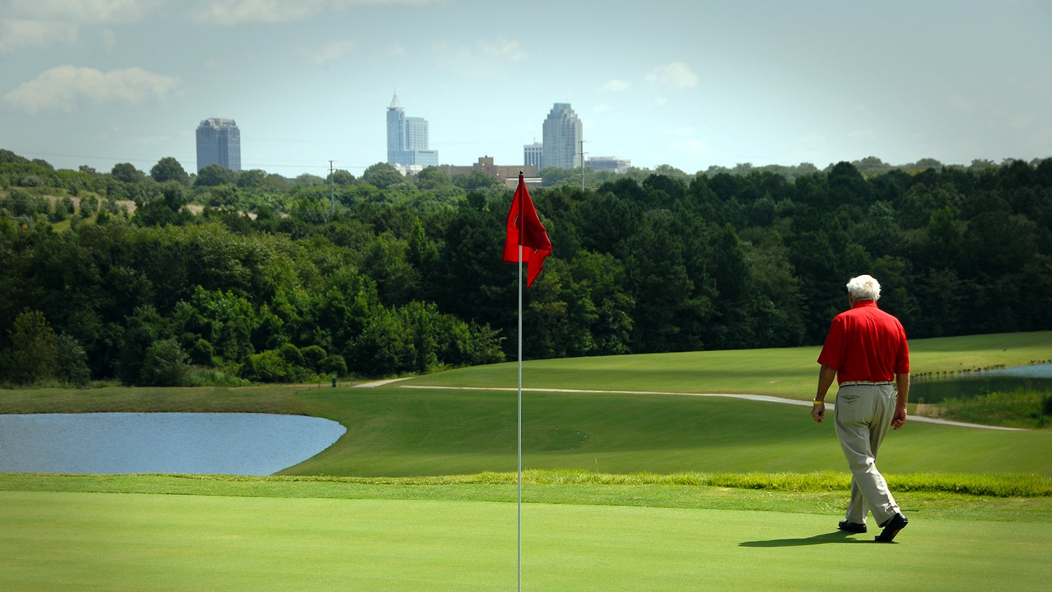 A golfer on the Lonnie Poole Golf Course admires the Raleigh skyline.