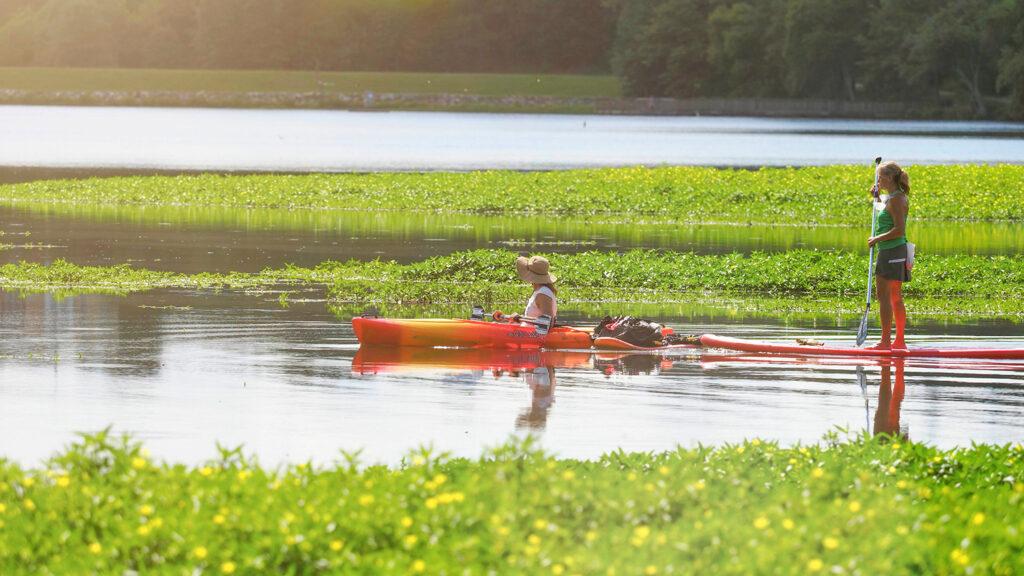 Two women paddling kayaks on Lake Raleigh.