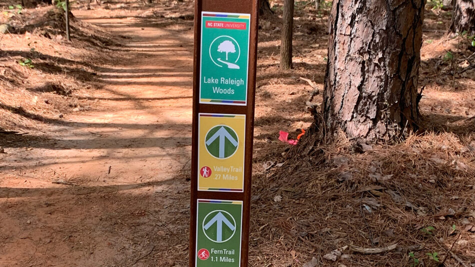 Signs pointing to various hiking and biking trails in Lake Raleigh Woods.