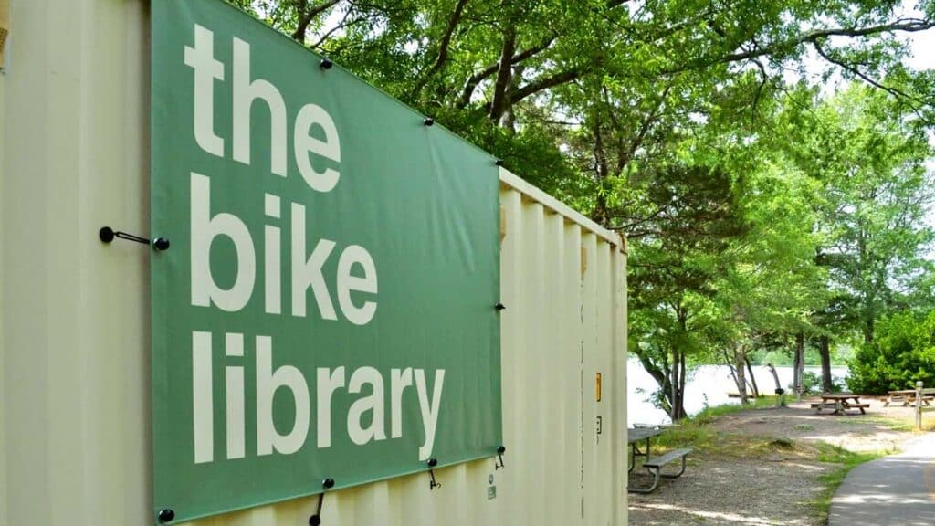 A shipping container from The Bike Library filled with bikes available to rent, right on Lake Raleigh's shoreline.