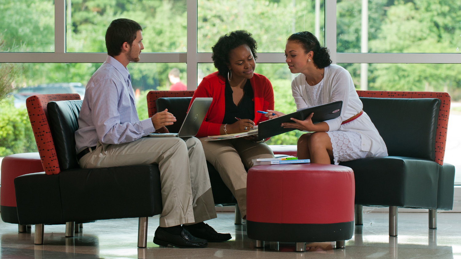 Three working professionals on laptops sit and collaborate on NC State's Centennial Campus.