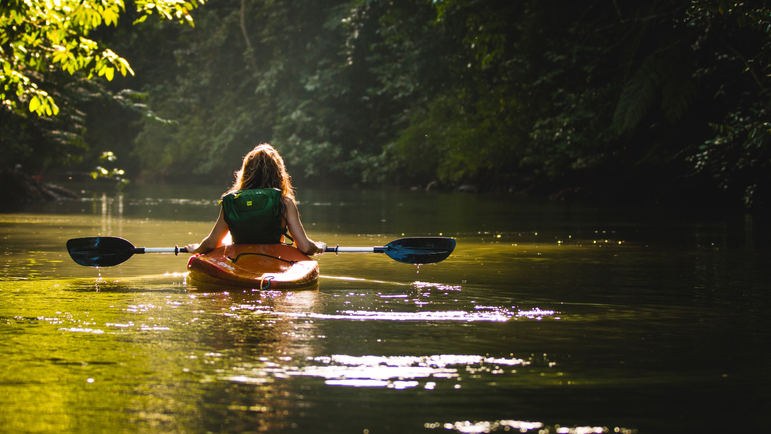 Woman paddling a kayak on smooth water.