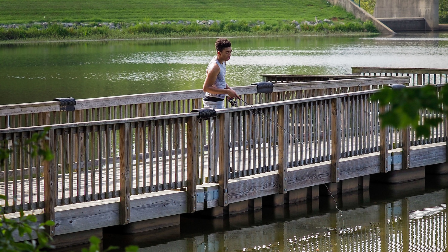 A man fishes on a fishing pier at Lake Raleigh Recreation Area.