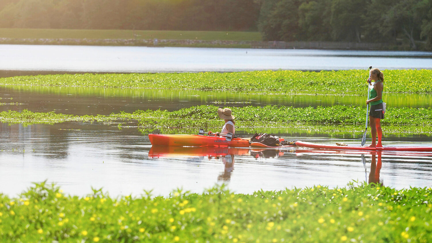 Two women paddling kayaks on Lake Raleigh.