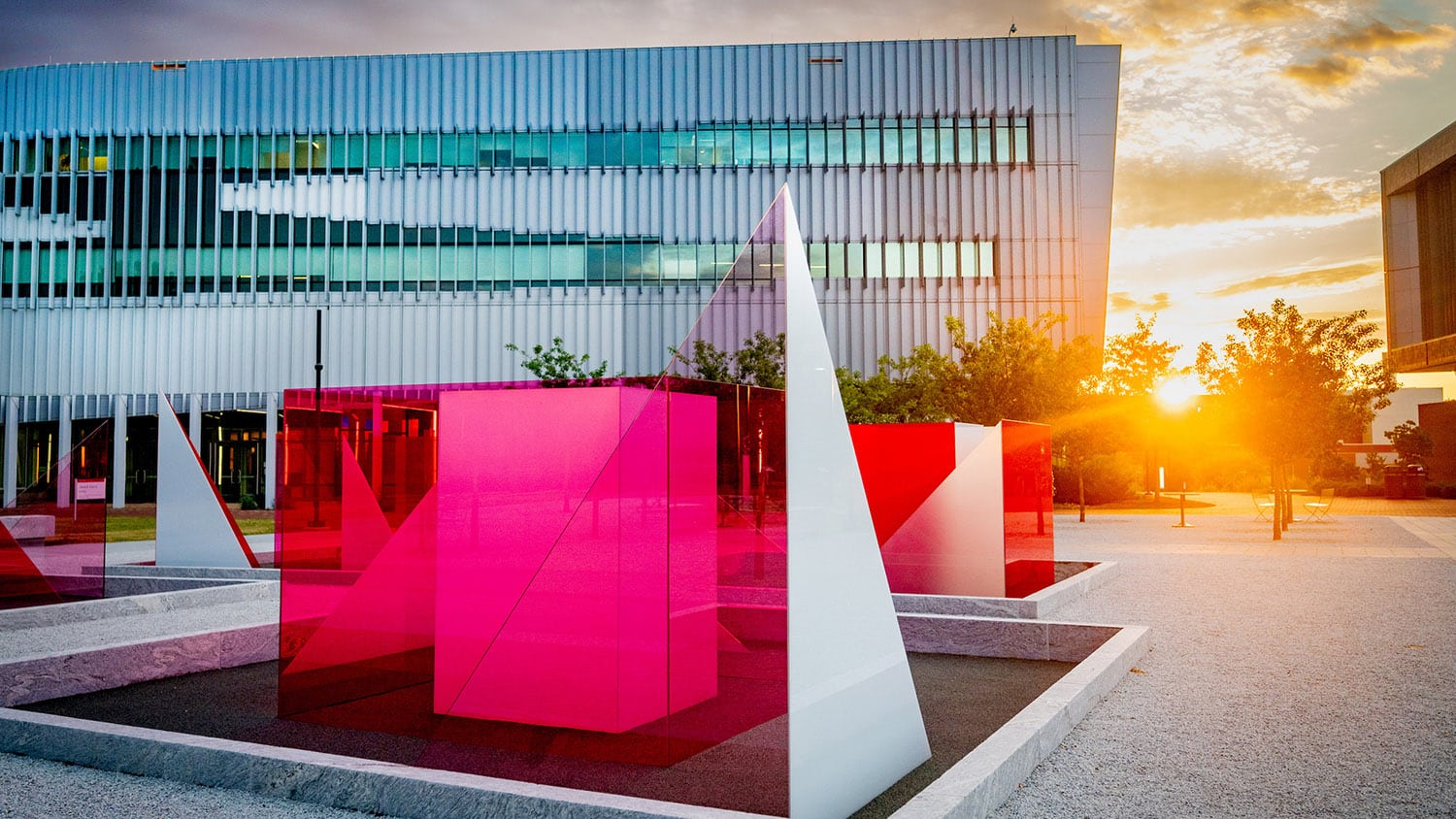 The sun sets on Centennial Campus behind the Hunt Library and the Reds and Whites art installation on the Engineering Oval.